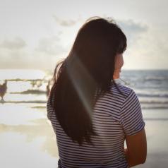 Girl stood looking towards the distant sea